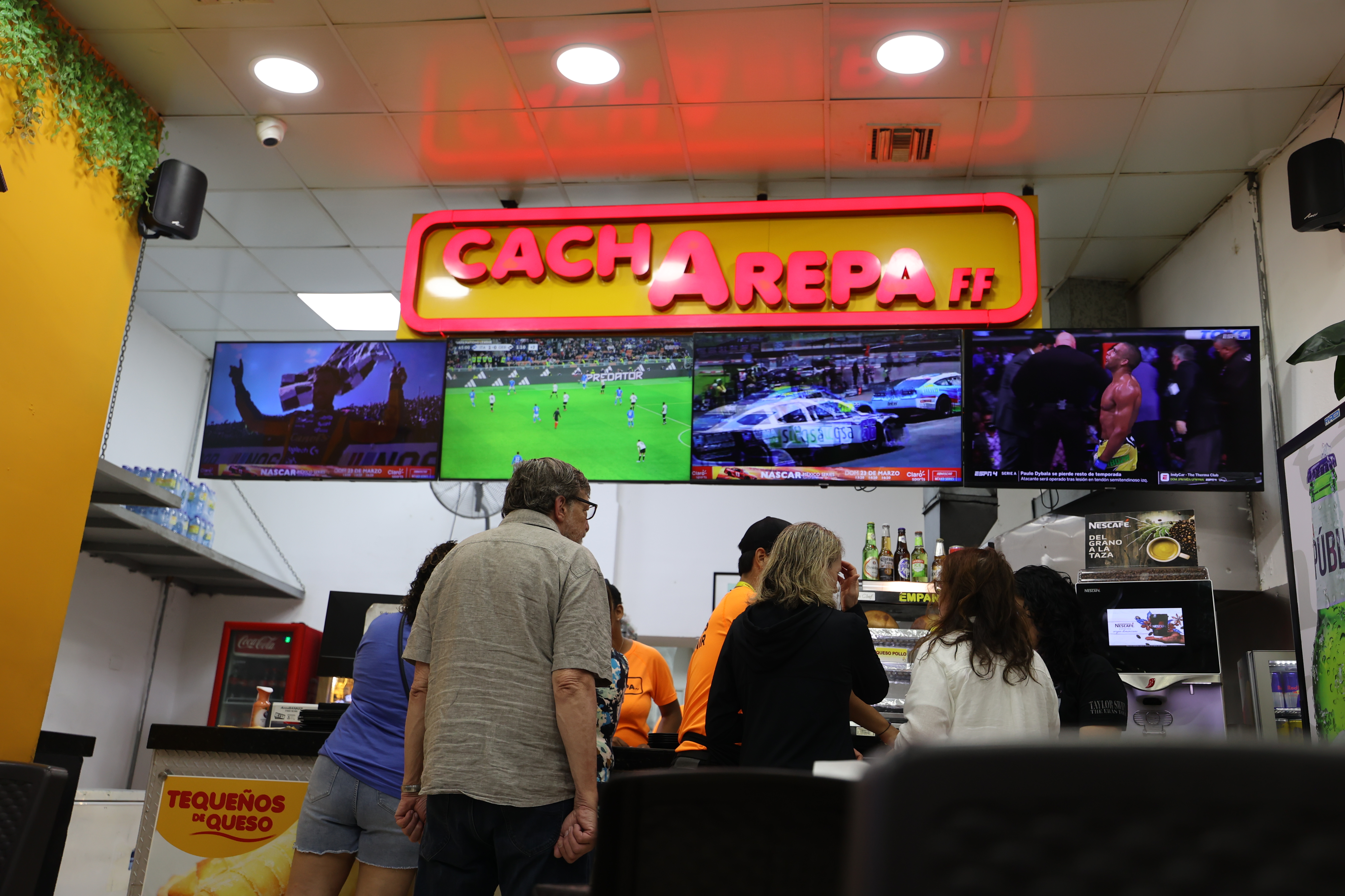 Bright neon Cachapa sign illuminating the restaurant counter area
