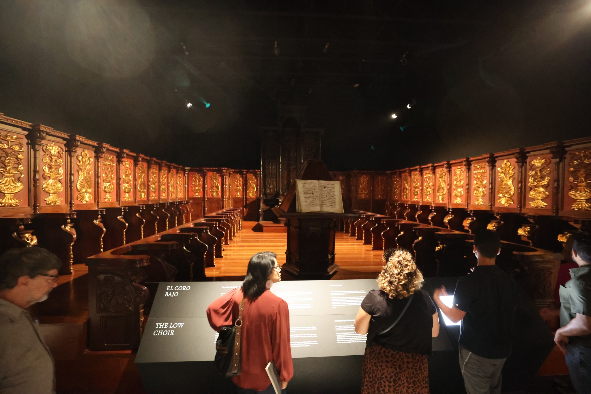 Historic choir stalls with ornate gold-leaf panels and central lectern with open manuscript