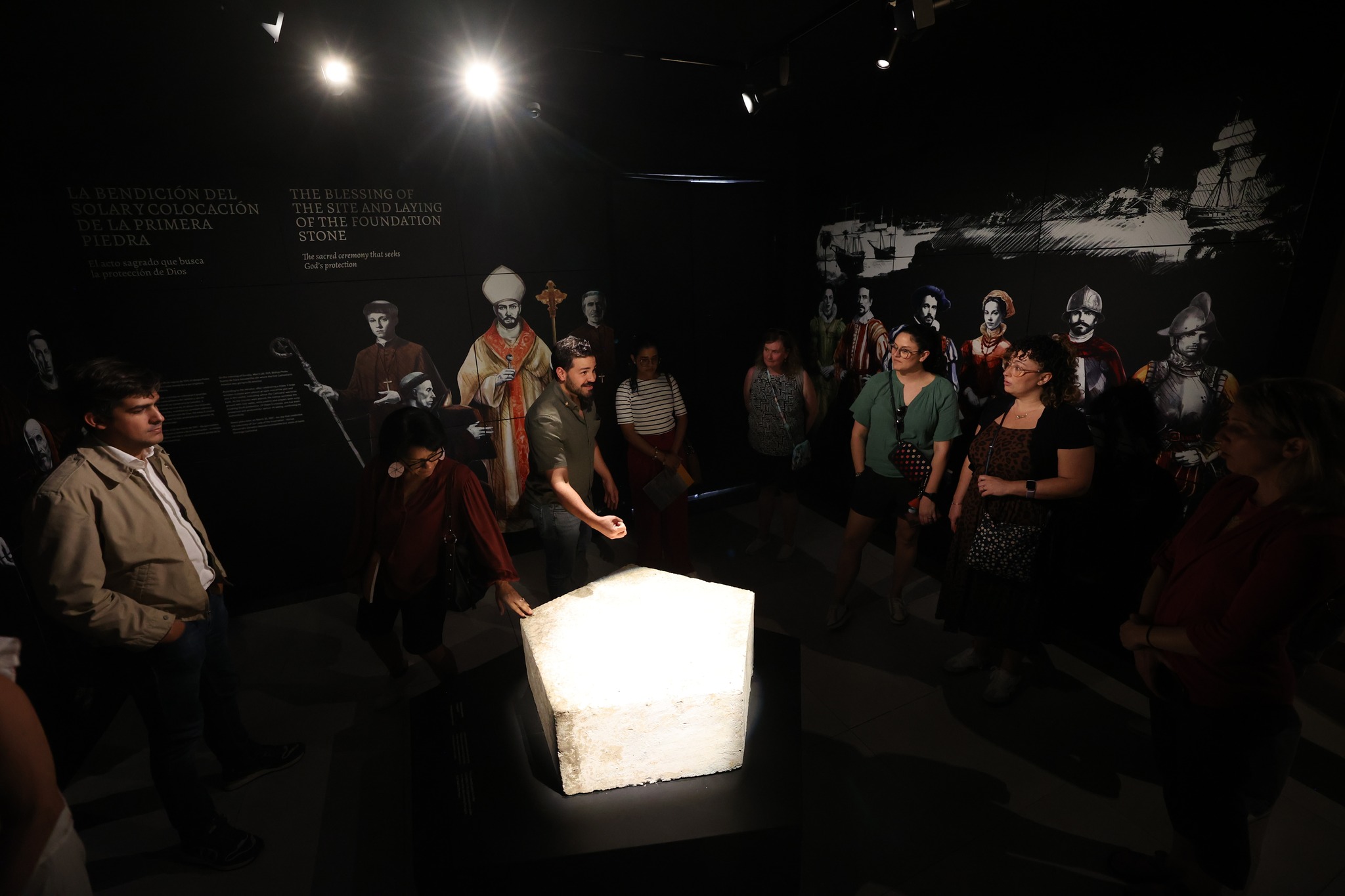 Interactive foundation stone exhibit with guide explaining ceremonial blessing to visitors