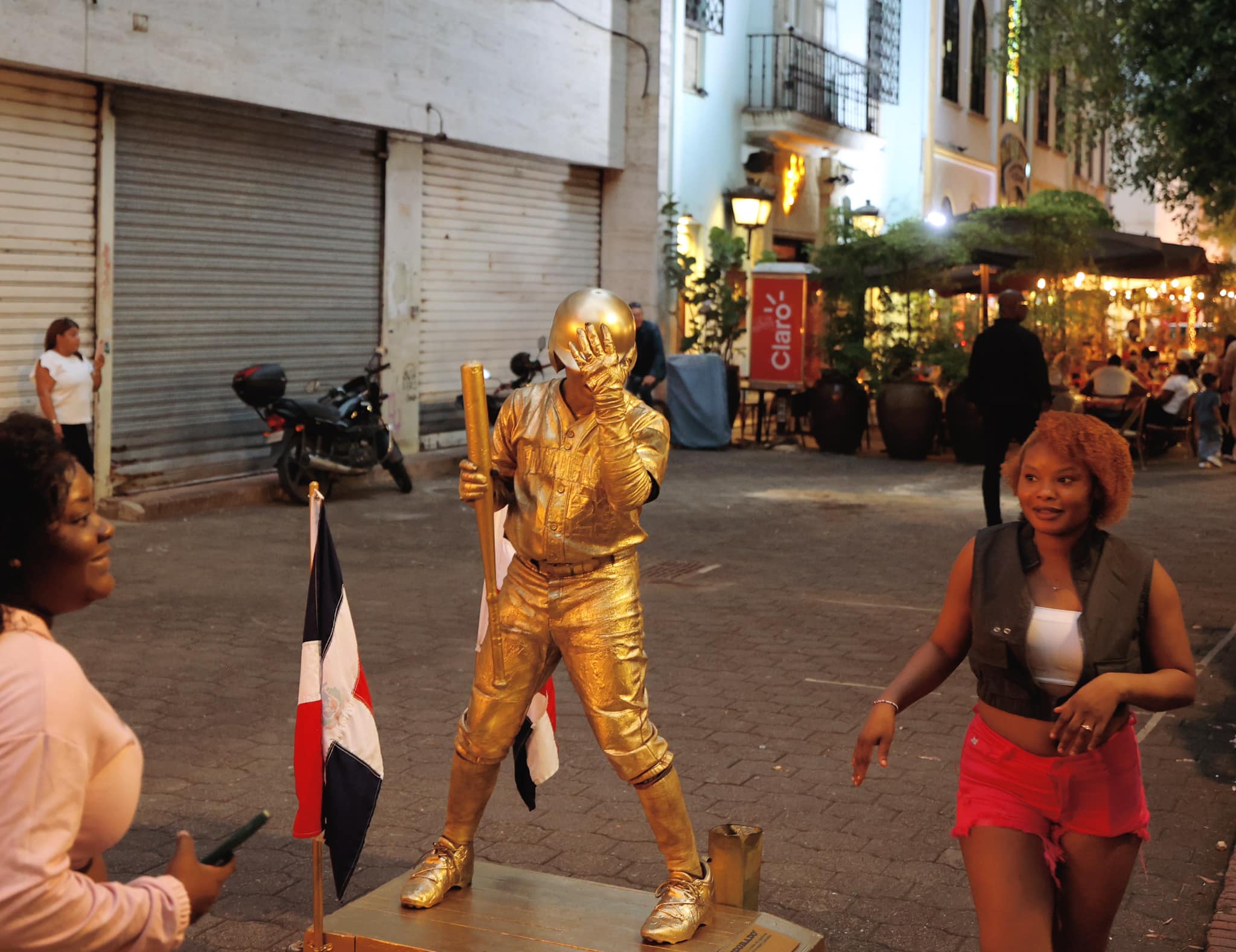 Golden baseball statue performer on street in Zona Colonial