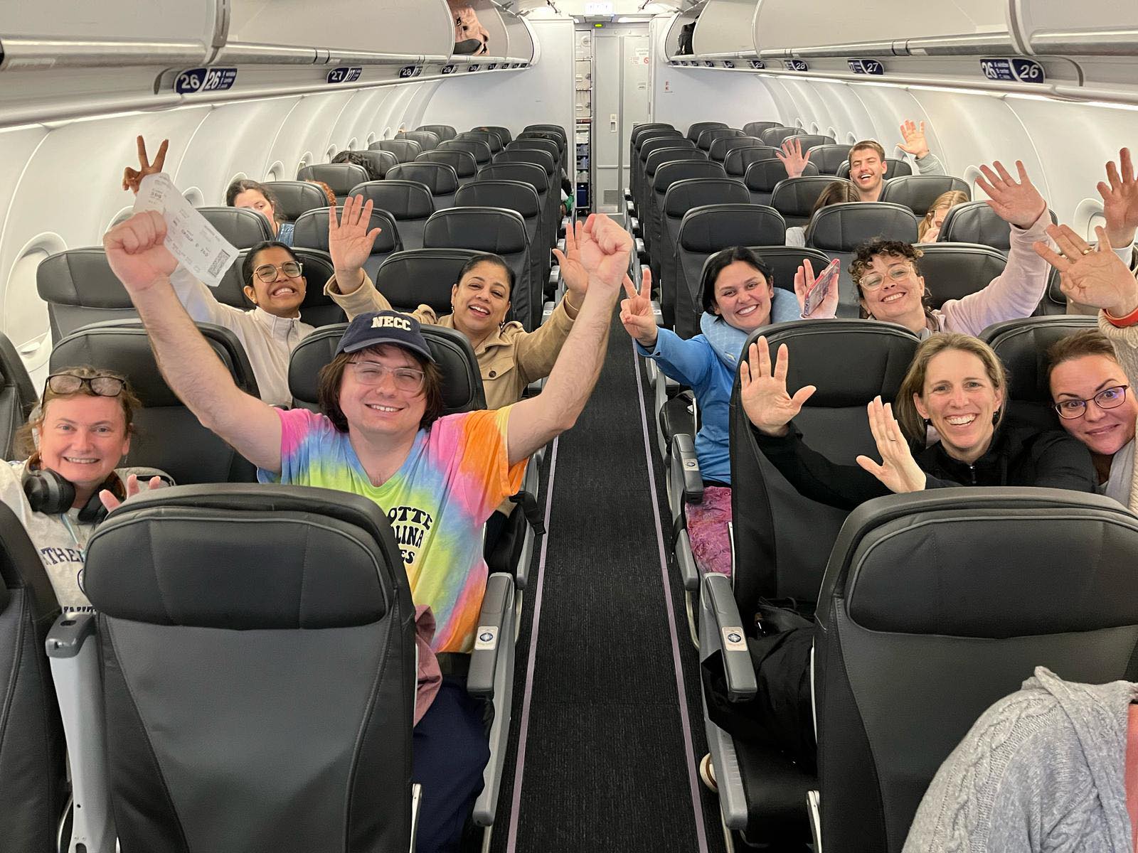 Jubilant delegation members with raised hands on return flight to Massachusetts