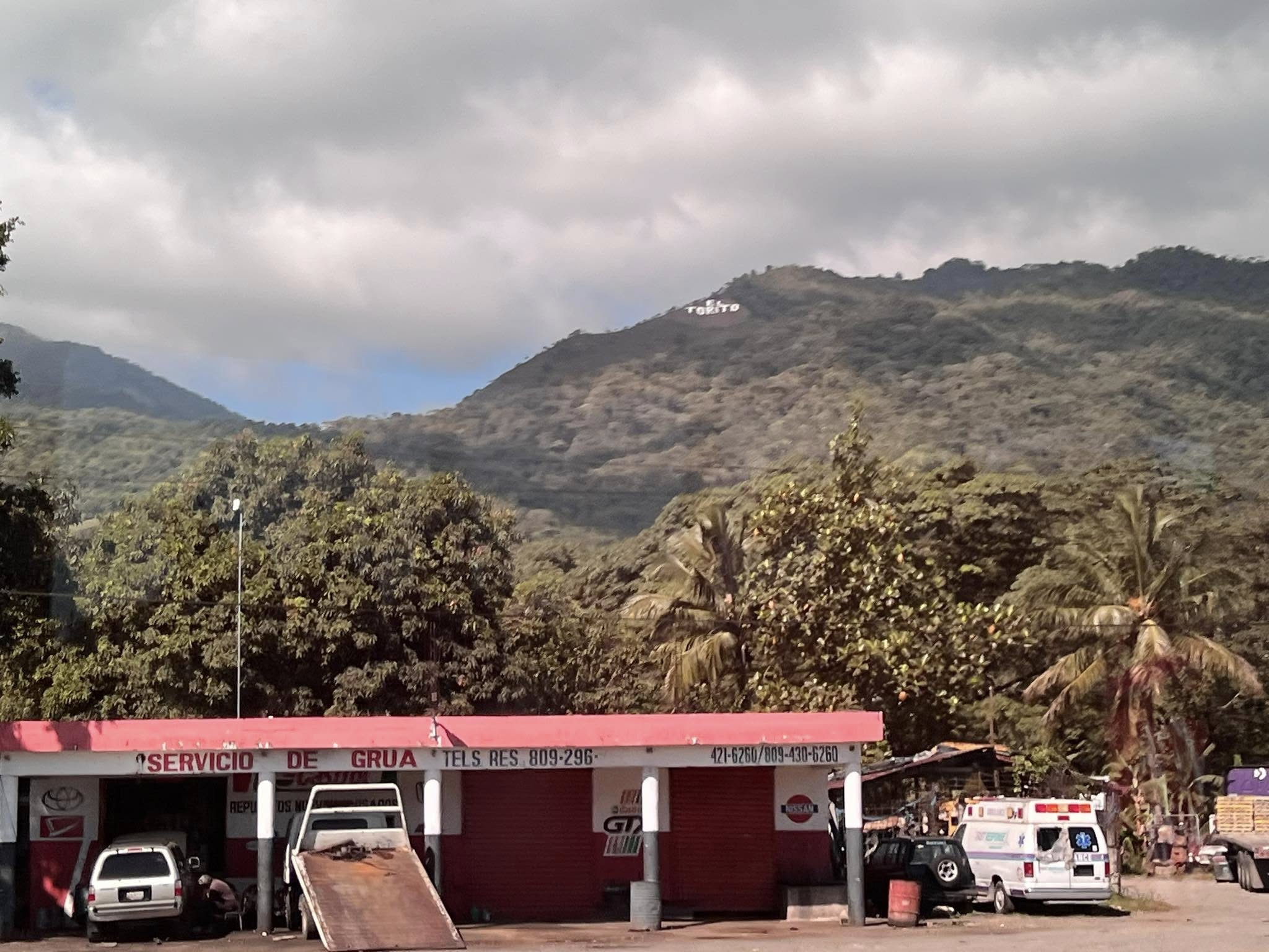 Mountain vista with 'Tetero' sign visible on hillside and roadside tow service building