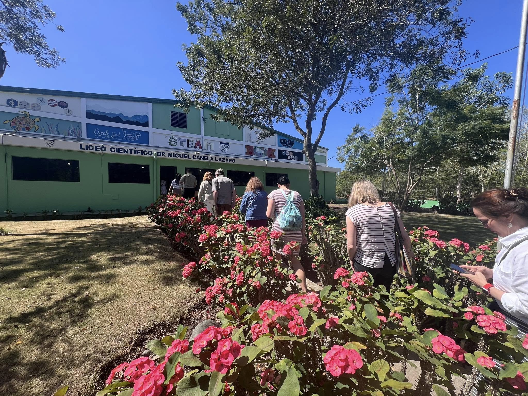 Approaching the school through a path lined with vibrant pink flowers