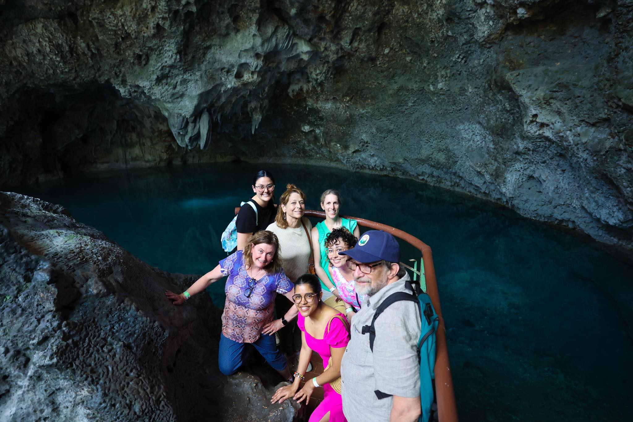 Group photo beside azure blue cave lake with limestone formations