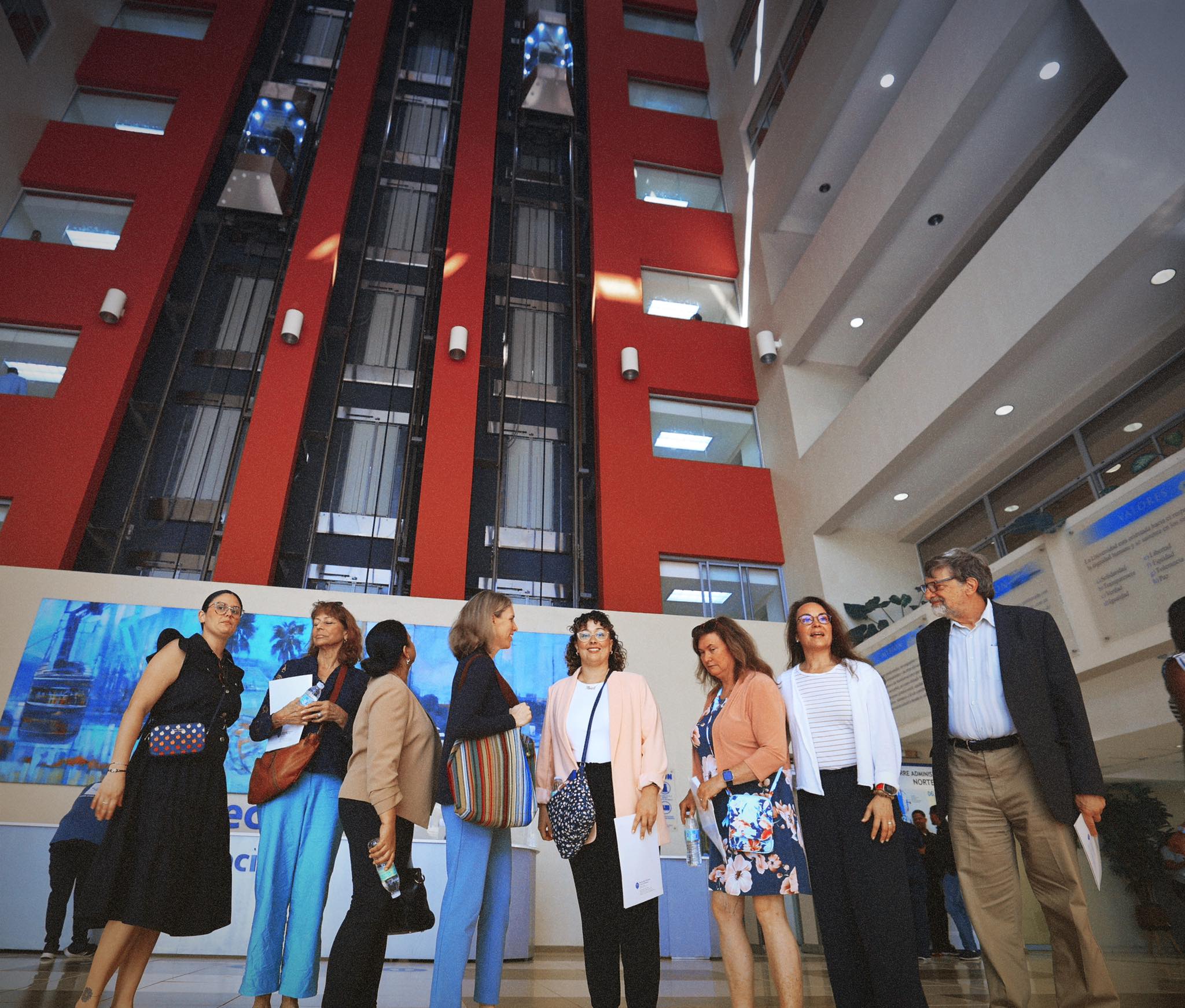 Our group conversing in the modern lobby of the UASD administrative tower with distinctive red architectural features